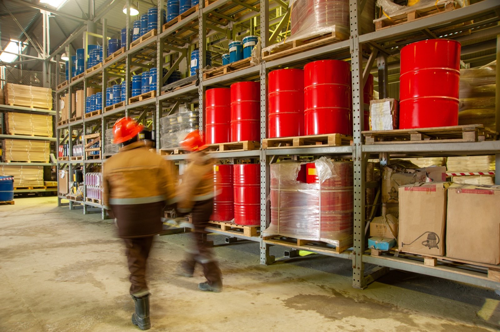 Cuve de retenție sub butoaie chimice depozitate pe paleți într-un depozit industrial