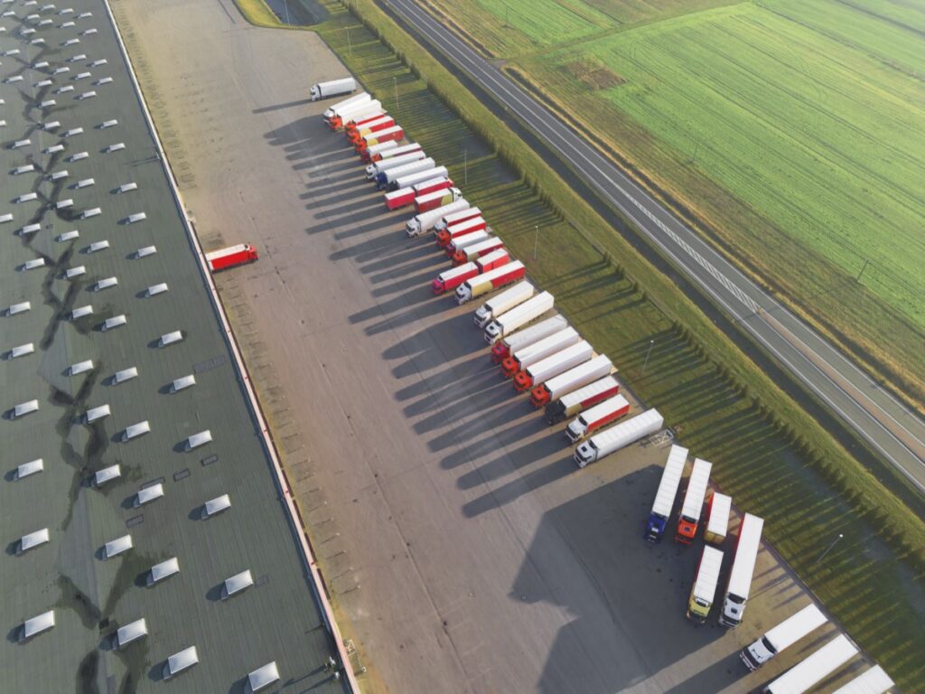 Flotă de camioane parcată într-un centru logistic, monitorizată prin GPS — vedere aeriană